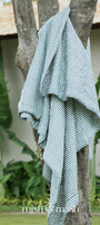 blue stripped jaipuri quilt draped over a tree branch with 'mish mish' branding in the corner.