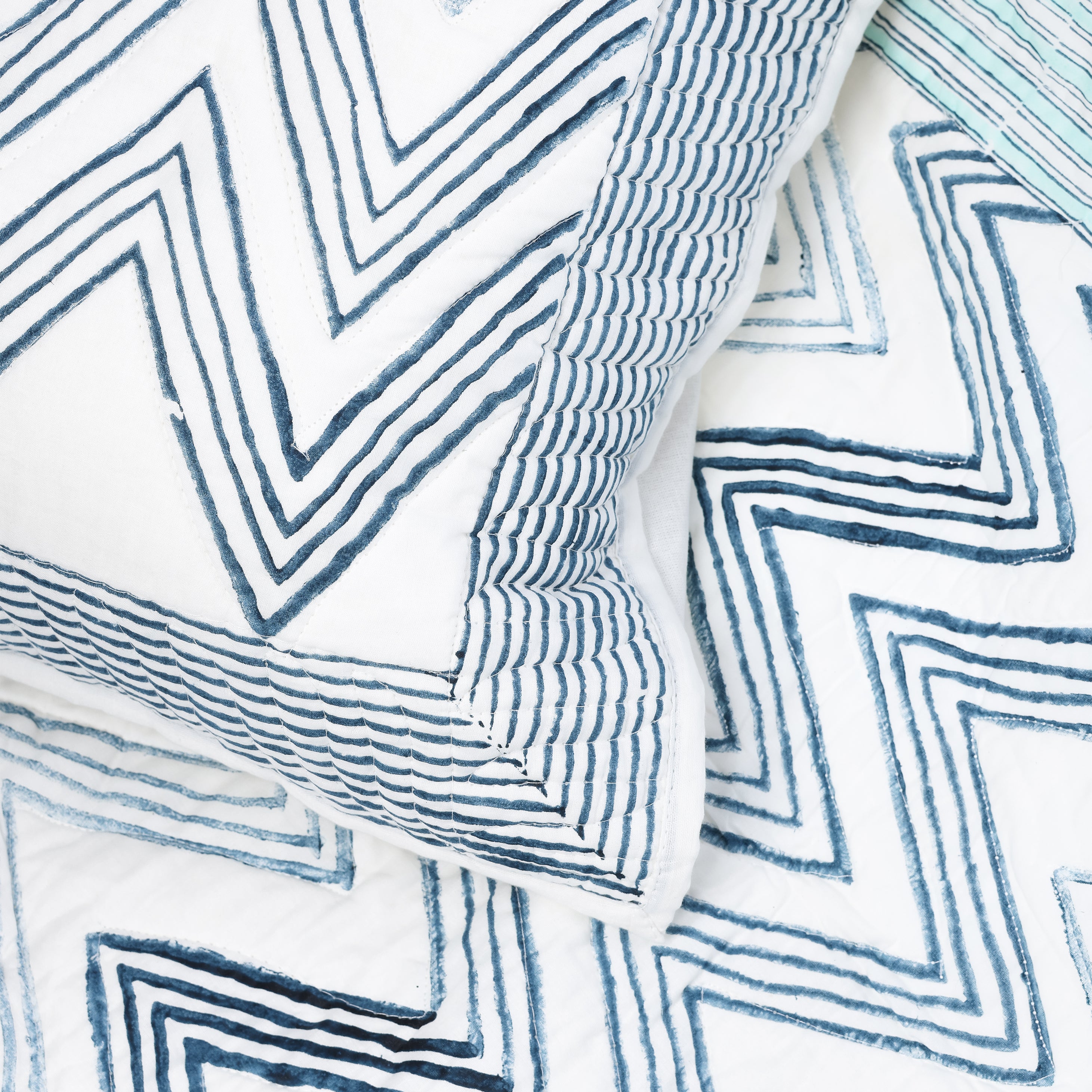 Reversible quilted bed spread with blue zigzag pattern on a white base