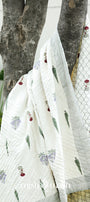 White quilt with floral block print draped over a tree branch outdoors. Buy cotton razai. Buy jaipur rajai.