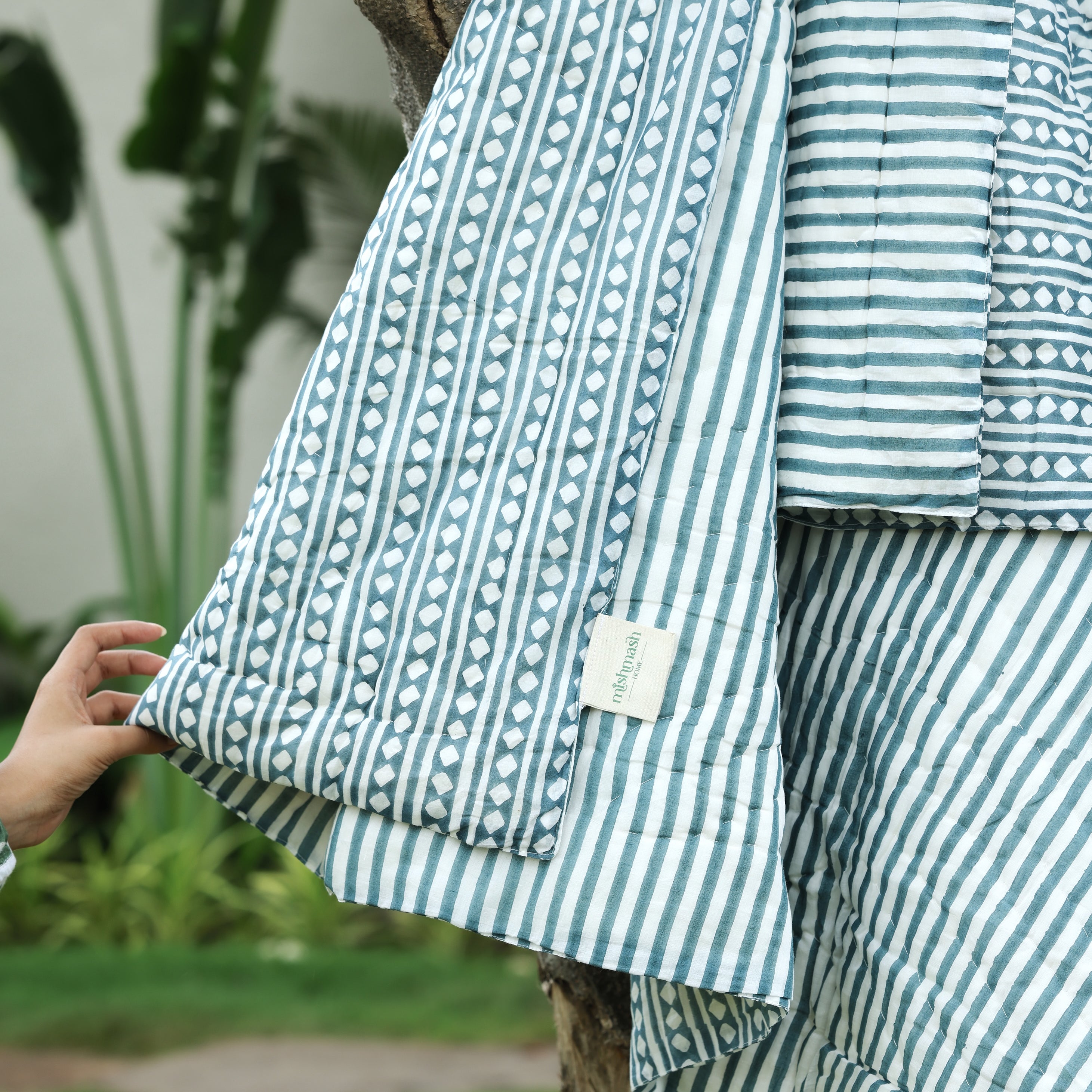 Striped jaipuri quits with a visible brand logo against a natural background. jaipuri razai.