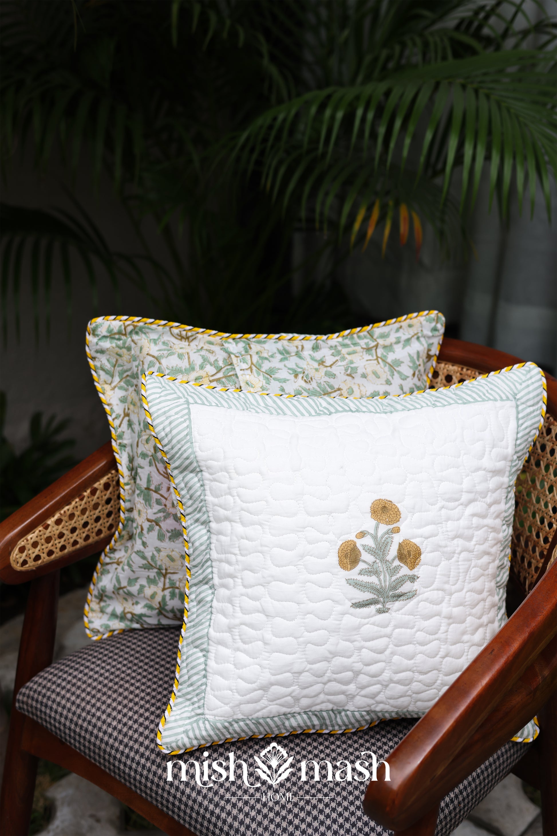 Two yellow cushion cover 16x16 on a chair with a plant in the background