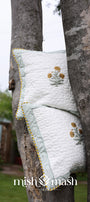 Quilted yellow Cushion cover with floral print hanging on a tree. Buy cushion covers online.