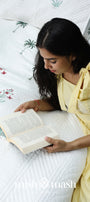 Woman reading a book on a bed with cotton bed cover perfect as a housewarming gift