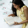 Woman reading a book on a bed with cotton bed cover perfect as a housewarming gift