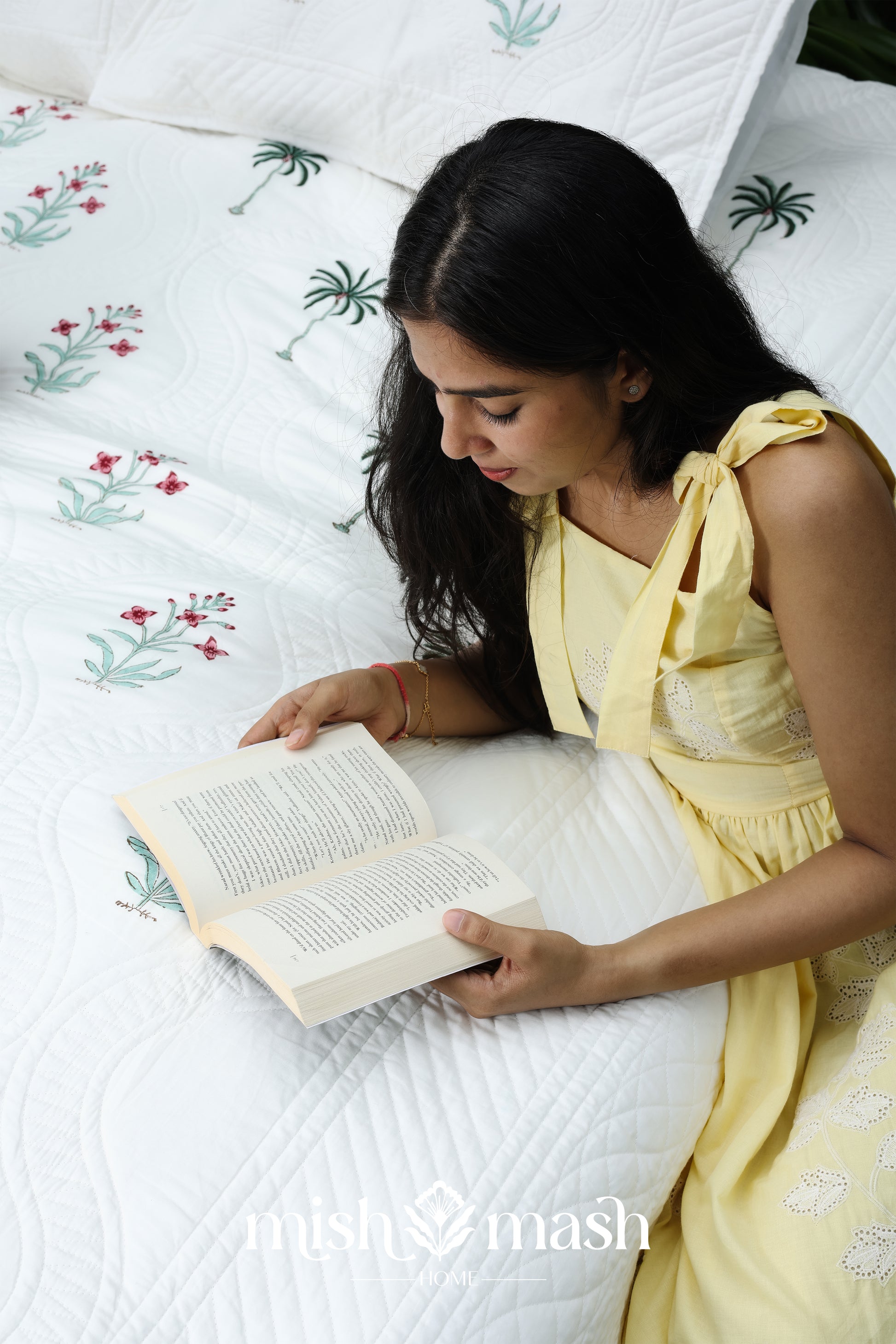Woman reading a book on a bed with cotton bed cover perfect as a housewarming gift