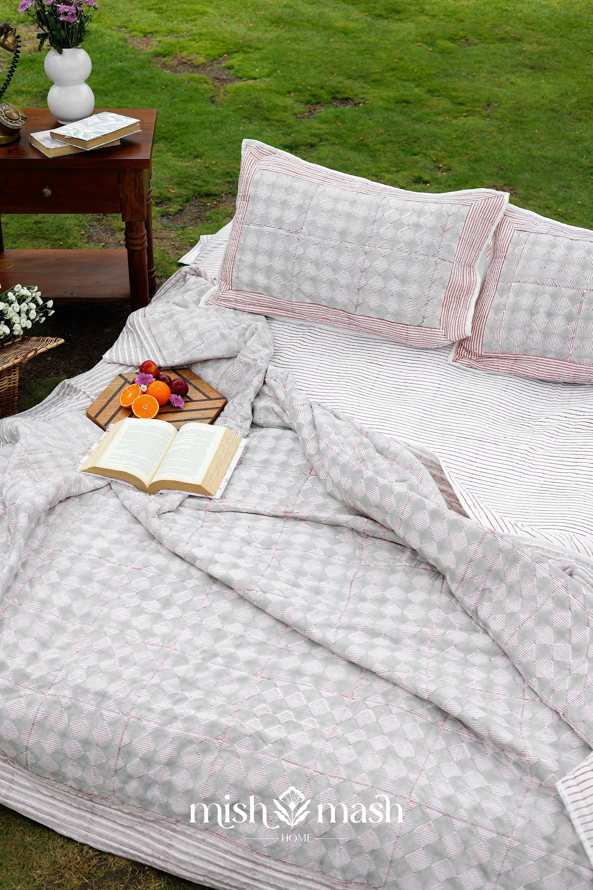 Outdoor setting with a bed covered in striped double bed sheet and pure cotton pillows.