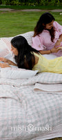 Two women reading books on a red and white checkered cotton bed spread outdoors made in pure cotton
