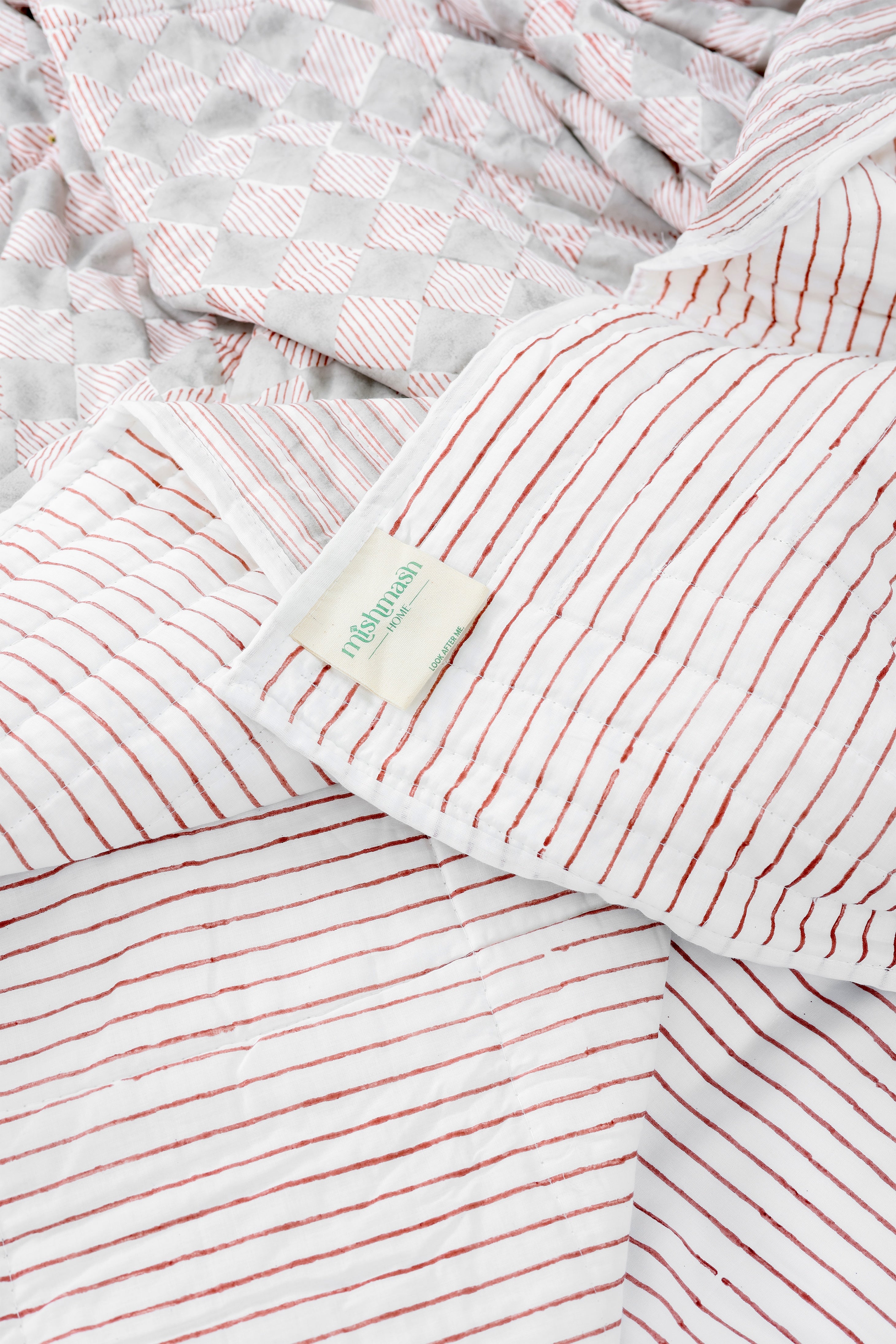Reversible cotton dohar blanket with red stripes on one side and grey diamonds on another