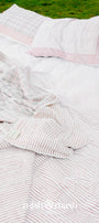 red and white striped pure cotton double bed sheet laying on green grass with two pillows 