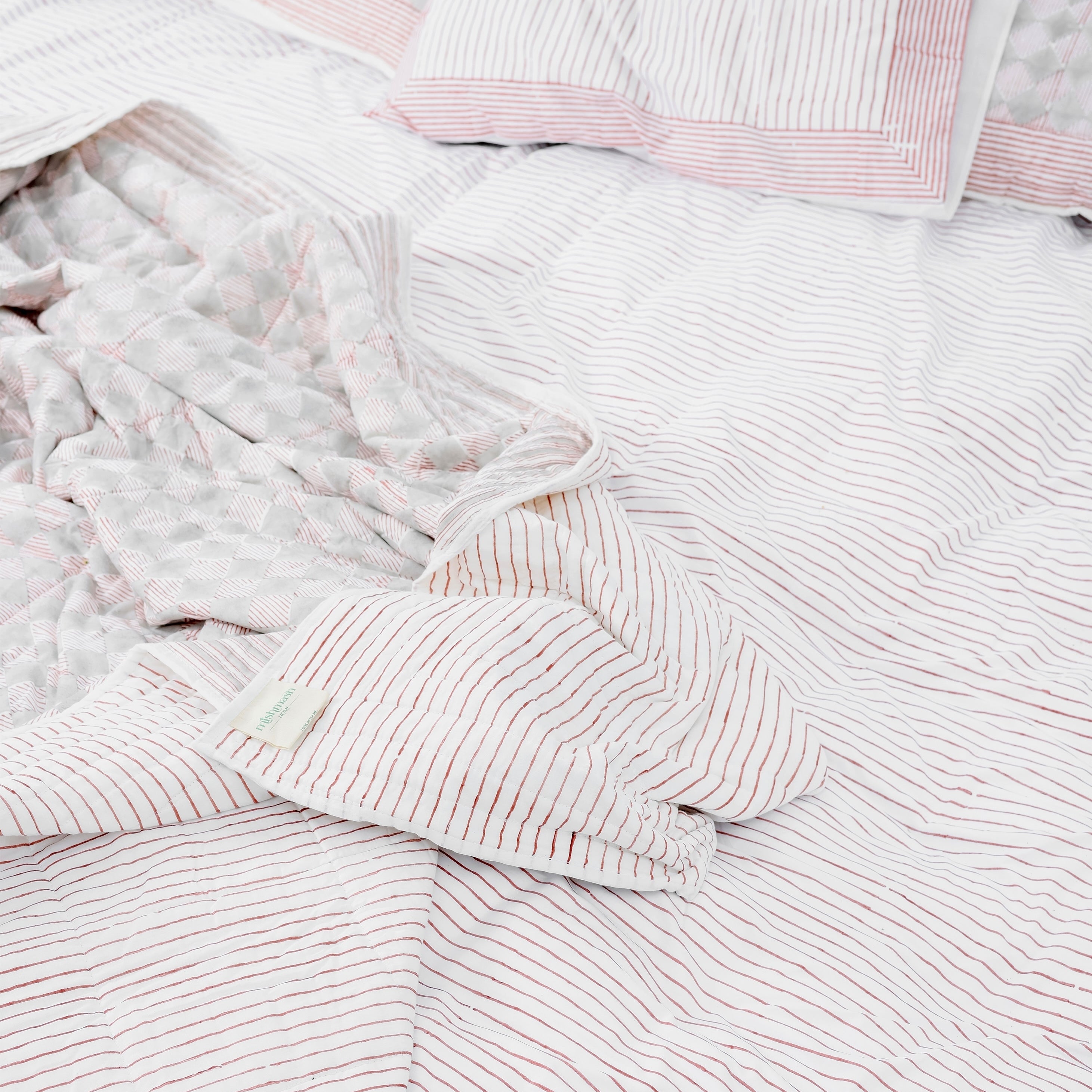 red and white striped pure cotton double bed sheet laying on green grass with two pillows 