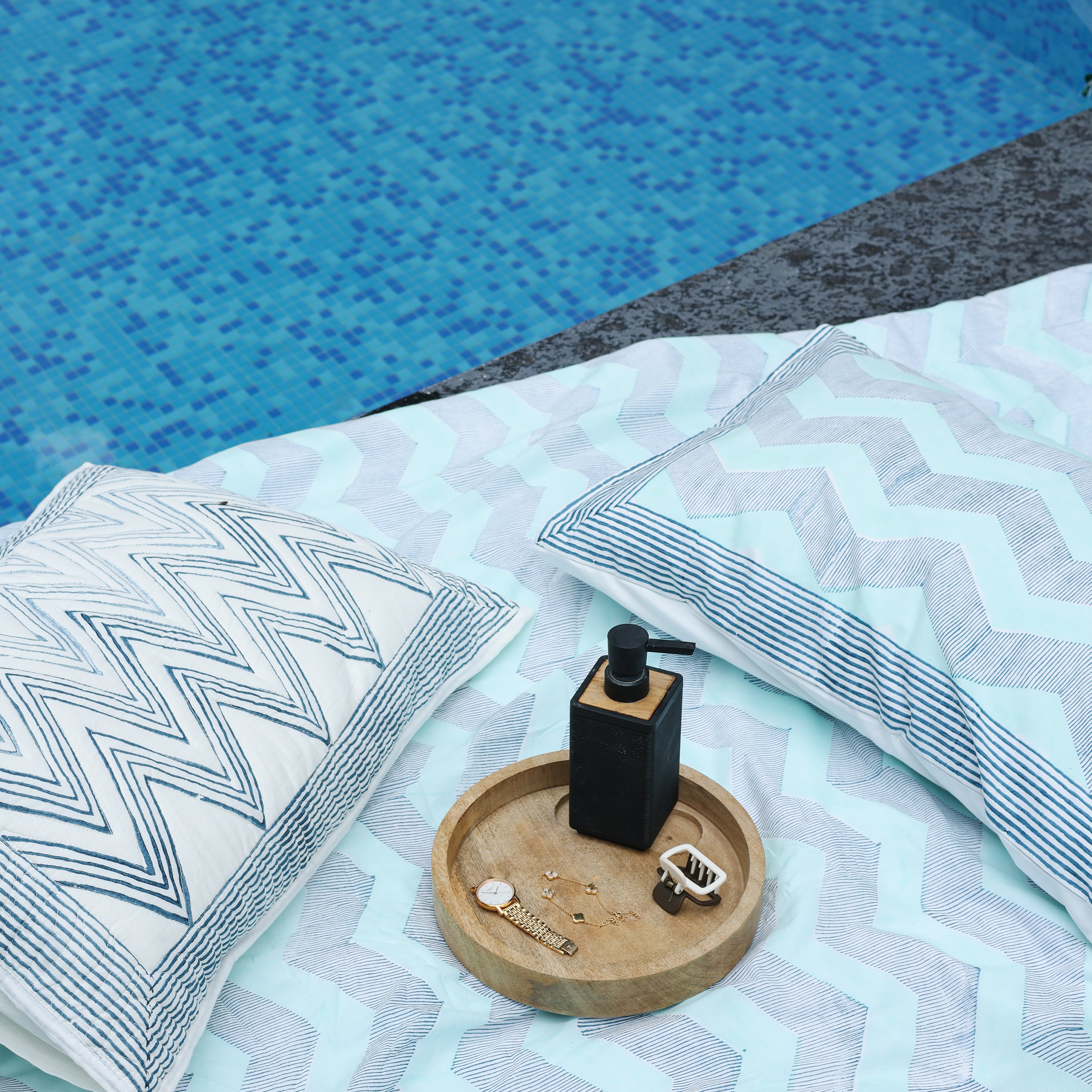 Blue double bed sheet with chevron pattern and matchig cotton pillow cover lying next to a pool