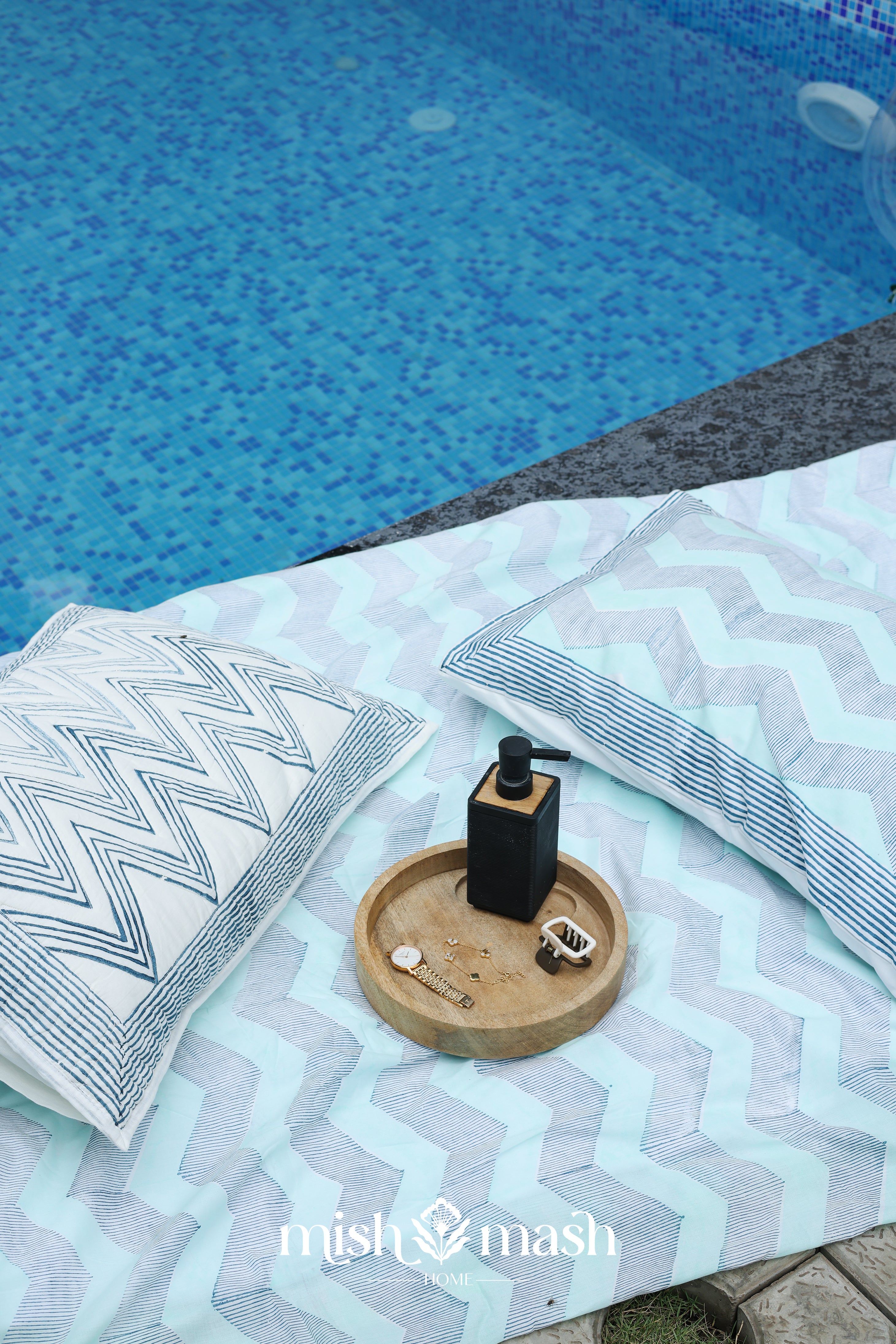 Blue double bed sheet with chevron pattern and matchig cotton pillow cover lying next to a pool