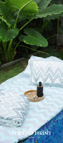 Outdoor setting with a blue chevron double bed sheet and folded reversible quilted bed spread along with two matching pillows
