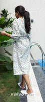 Woman in a floral cotton bath robe standing by a poolside with plants around. Buy bath robes for brides.