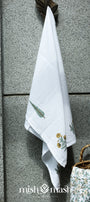 White towel hanging on a textured wall. Ladies bath towel with yellow floral print.
