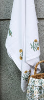 Woven basket and floral ladies bath towel against a textured wall. Buy bath linen online.