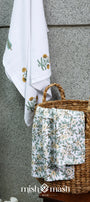 Woven basket having two hand towels and a quick dry bath towel against a textured wall.