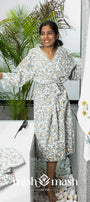 Woman wearing a floral cotton bathrobe standing next to two hand towels and a cotton bath towel. Bath set of 4.
