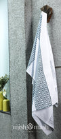 bath Towel for men with geometric pattern hanging on a wall next to a window. Quick dry cotton bath linen.