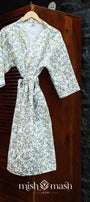 Floral-patterned cotton bath robe hanging on a wooden door with a stone wall background. Bombay dyeing bath robe for women.