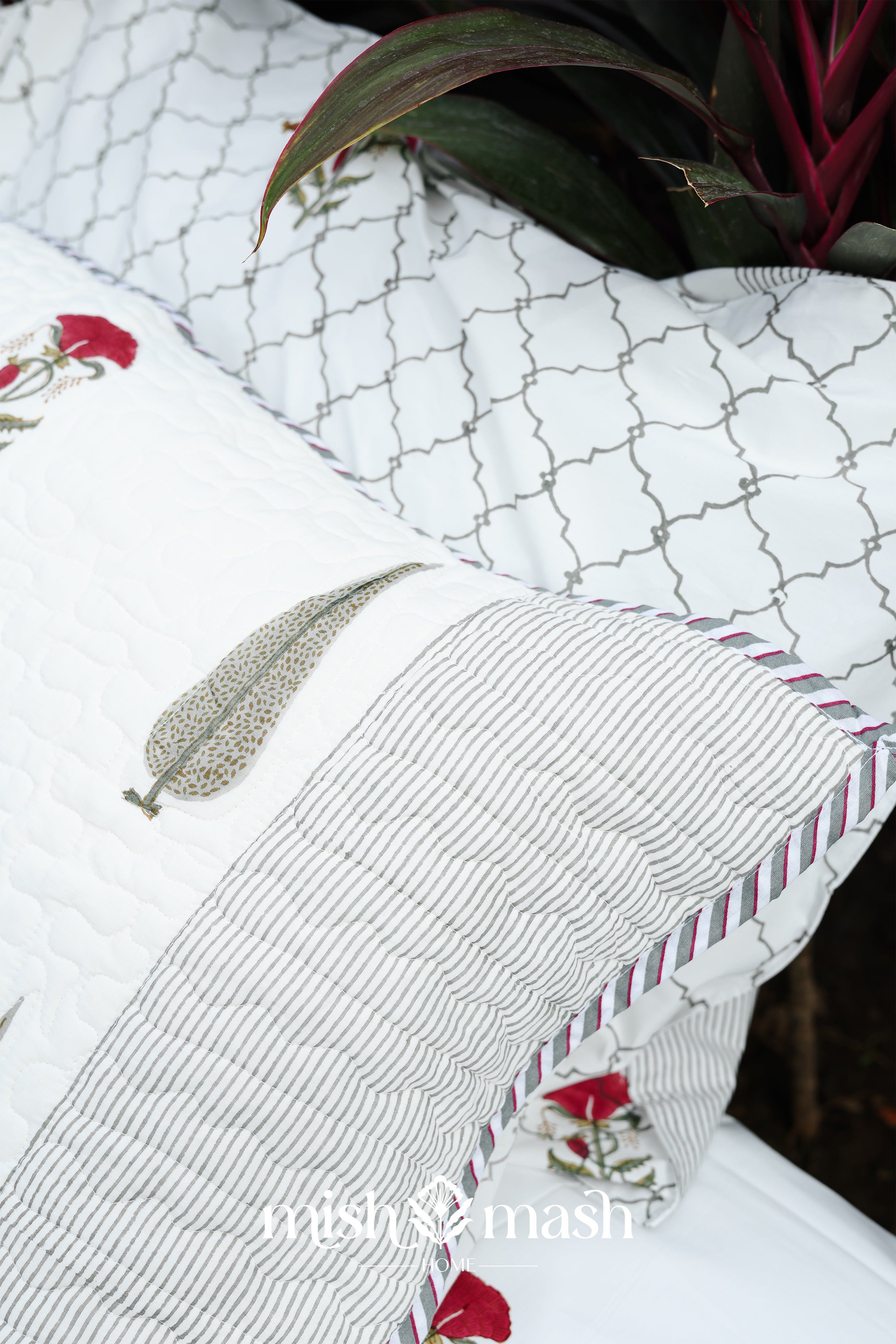 Close-up of a white cotton pillow of a cotton bed cover with floral print and  brand name: Mishmash.