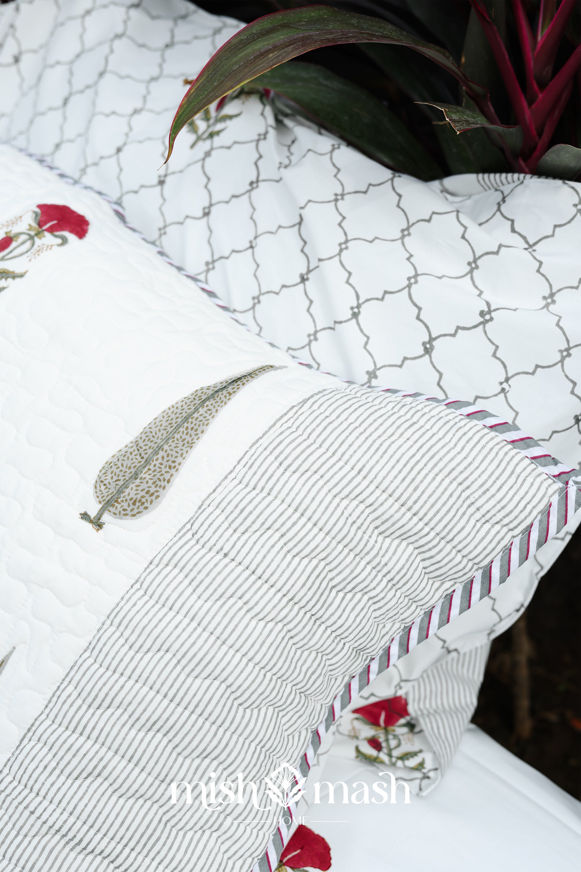 Close-up of a white cotton pillow of a cotton bed cover with floral print and  brand name: Mishmash.