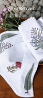 Set of white cotton hand towels with floral print on a wooden surface with a stone background. Spaces towels. 