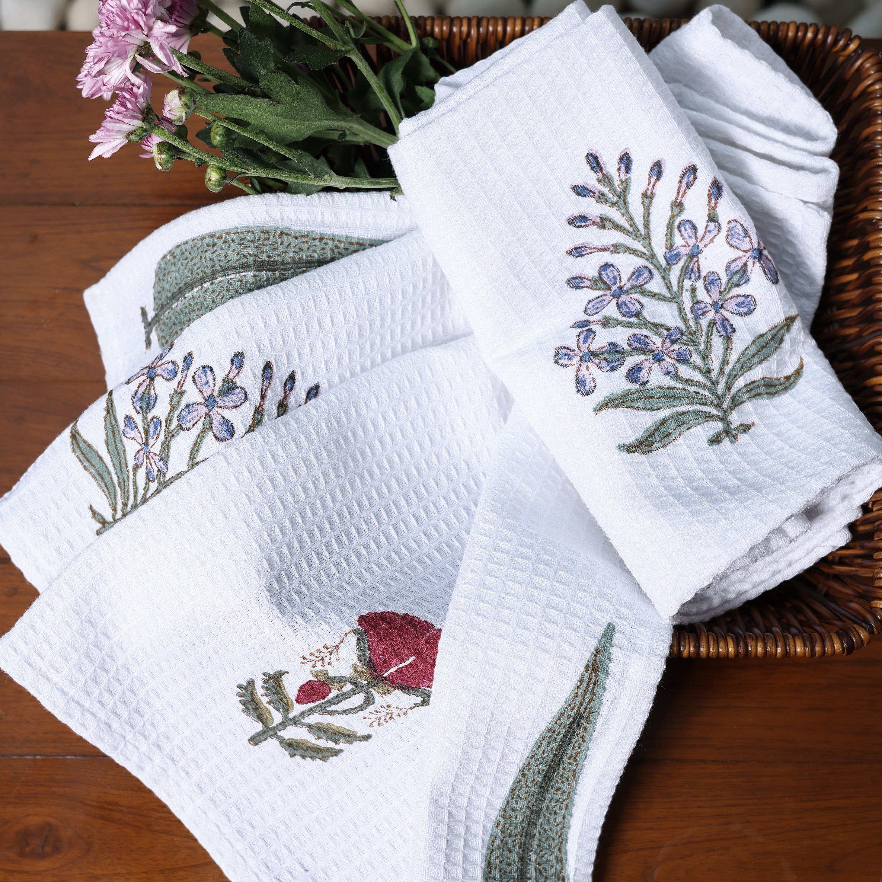 Set of white cotton hand towels with floral print on a wooden surface with a stone background. Spaces towels. 