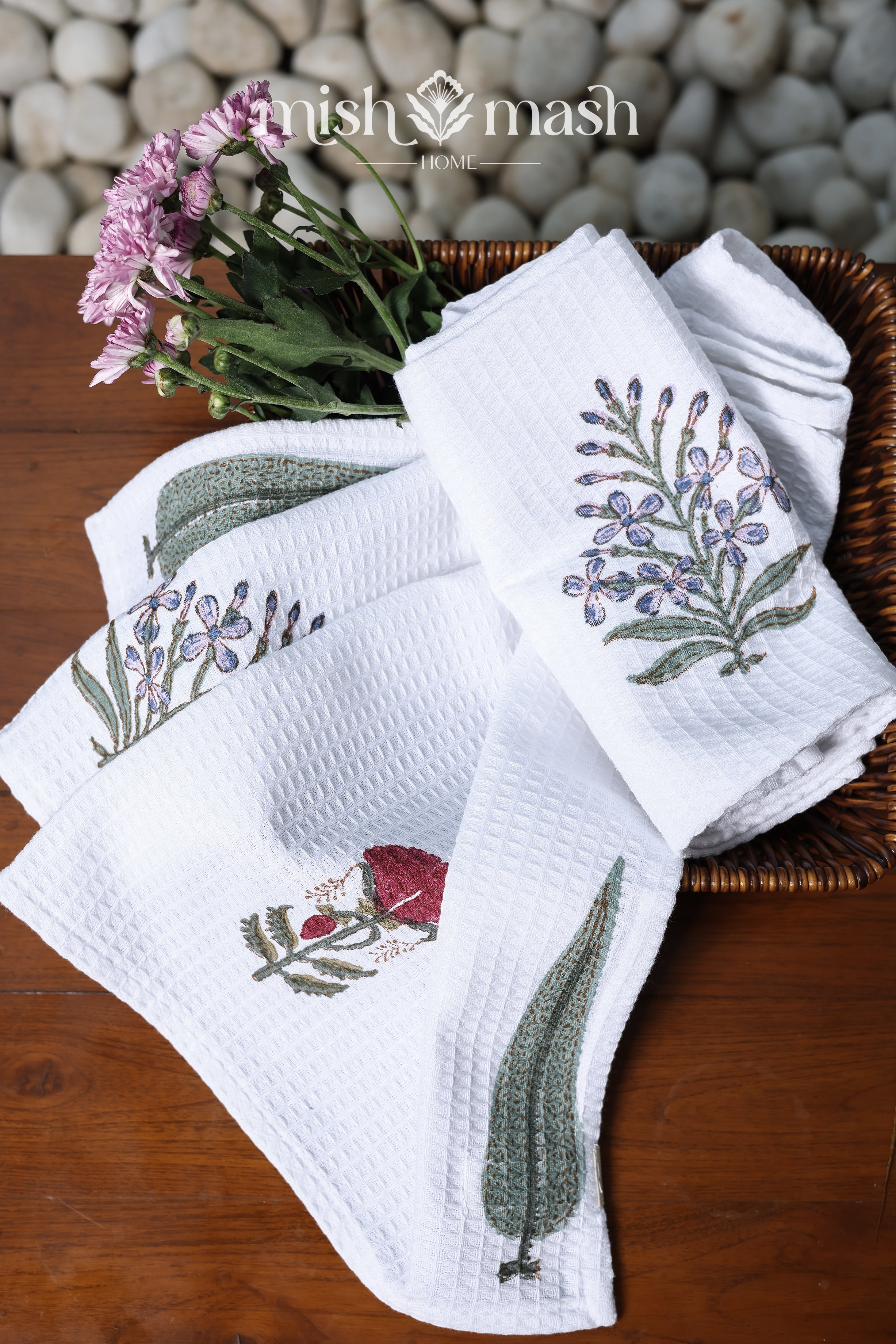 Set of white cotton hand towels with floral print on a wooden surface with a stone background. Spaces towels. 