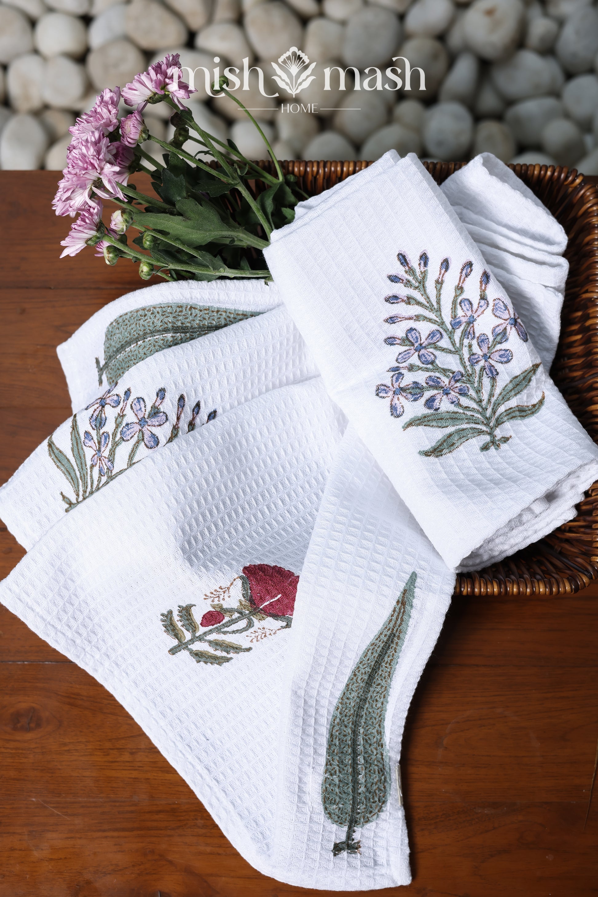 Set of white cotton hand towels with floral print on a wooden surface with a stone background. Spaces towels. 