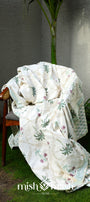 White floral cotton dohar blanket draped over a chair with palm motifs handprinted