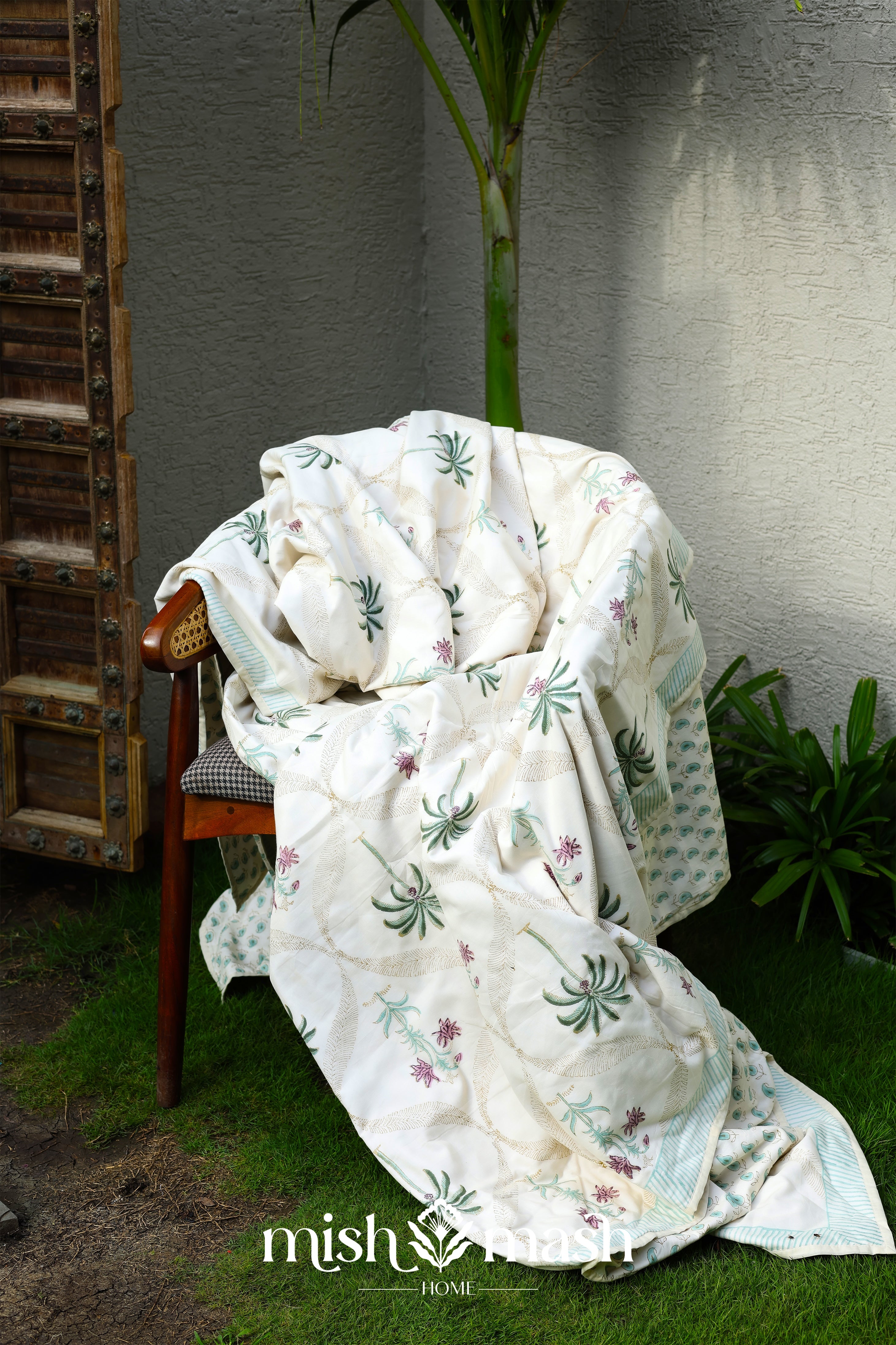White floral cotton dohar blanket draped over a chair with palm motifs handprinted