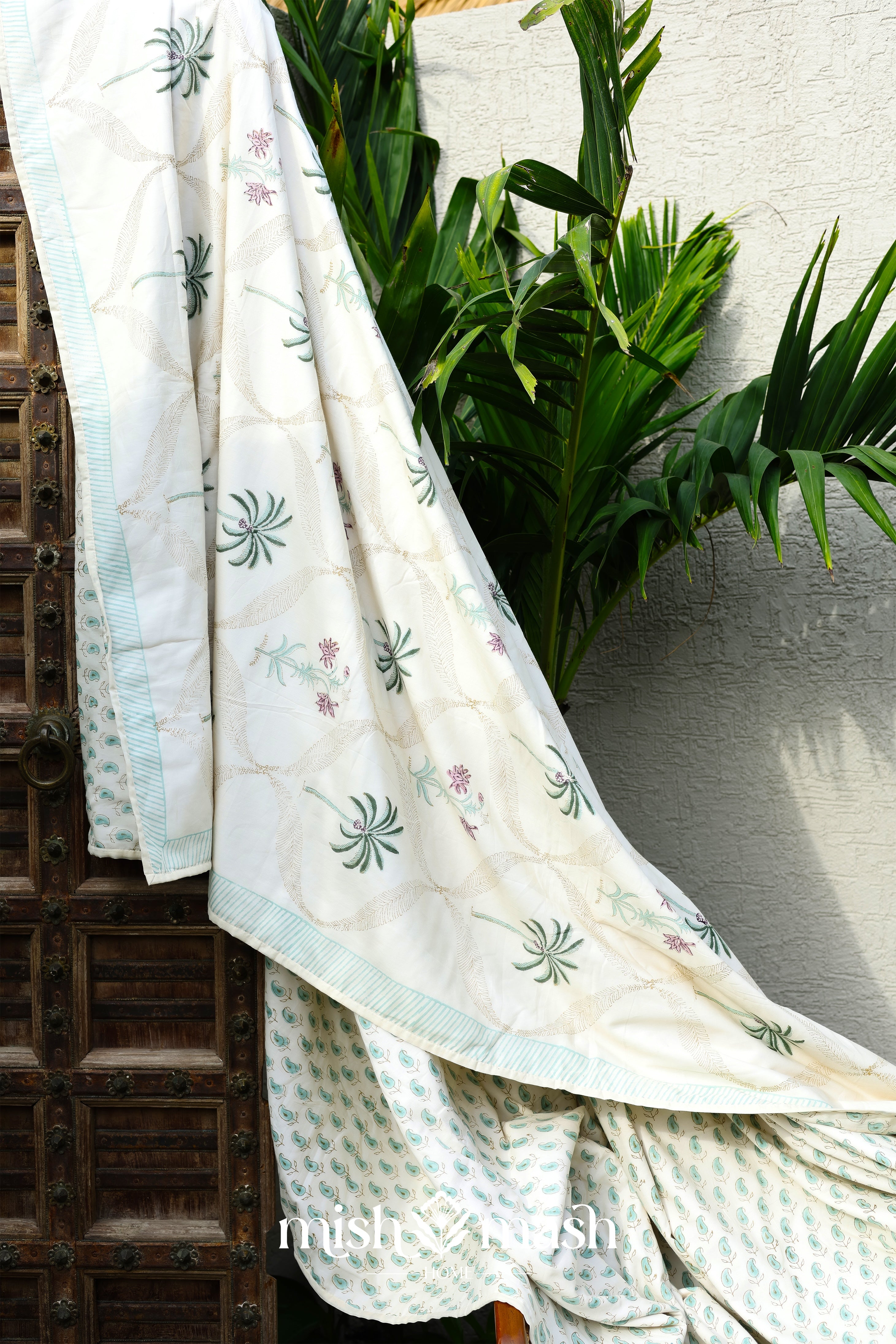Light yellow cotton summer blanket with green palm trees and floral patterns draped over a chair. Buy cotton dohar online.