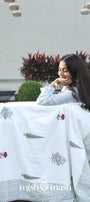 Woman wrapped in a white floral cotton dohar blanket with 'mish mash' branding in an outdoor setting. Cotton dohar.
