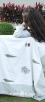 Person holding a white summer blanket with floral patterns in an outdoor setting. Buy cotton dohar blanket.