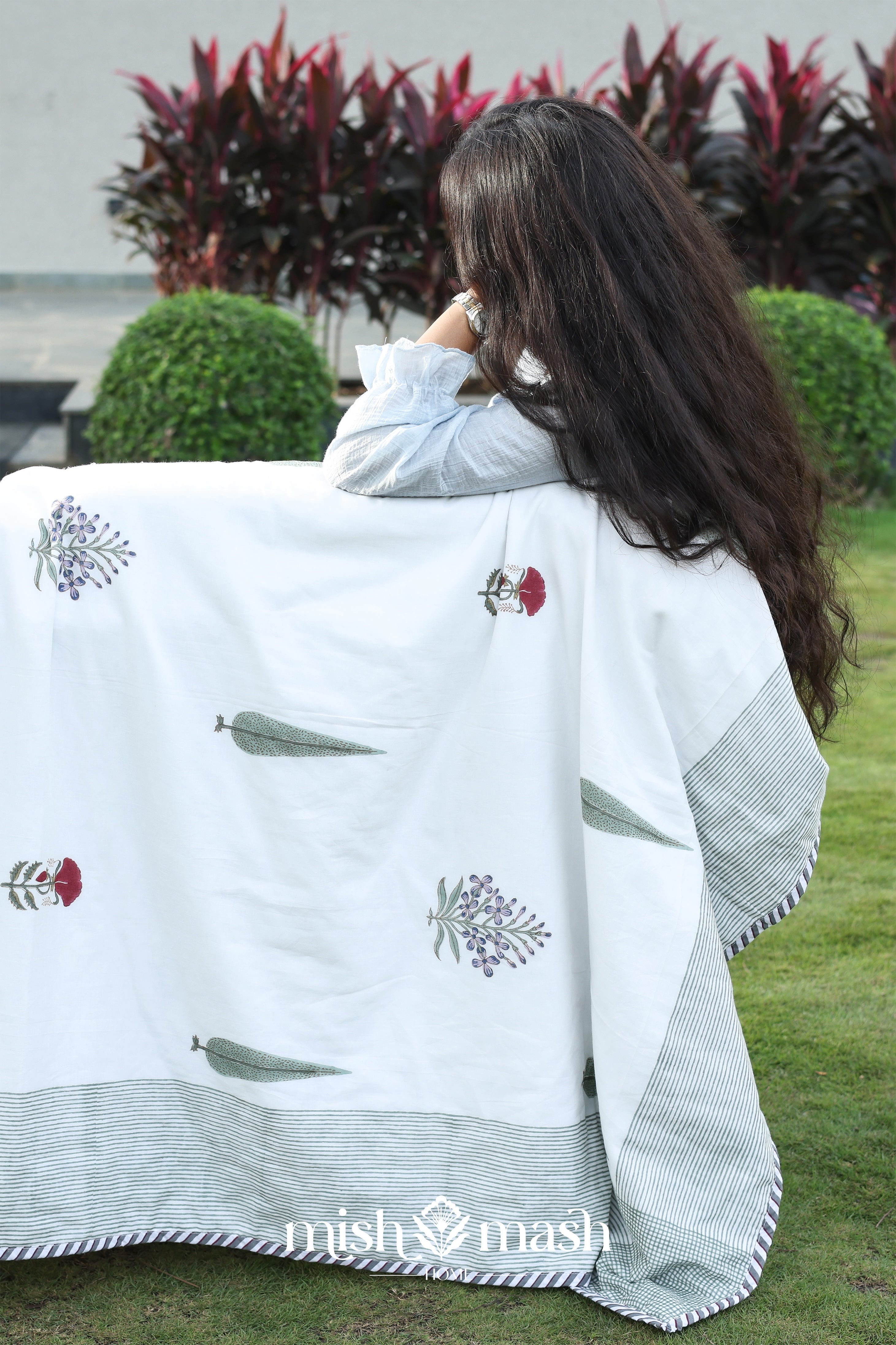 Person holding a white summer blanket with floral patterns in an outdoor setting. Buy cotton dohar blanket.
