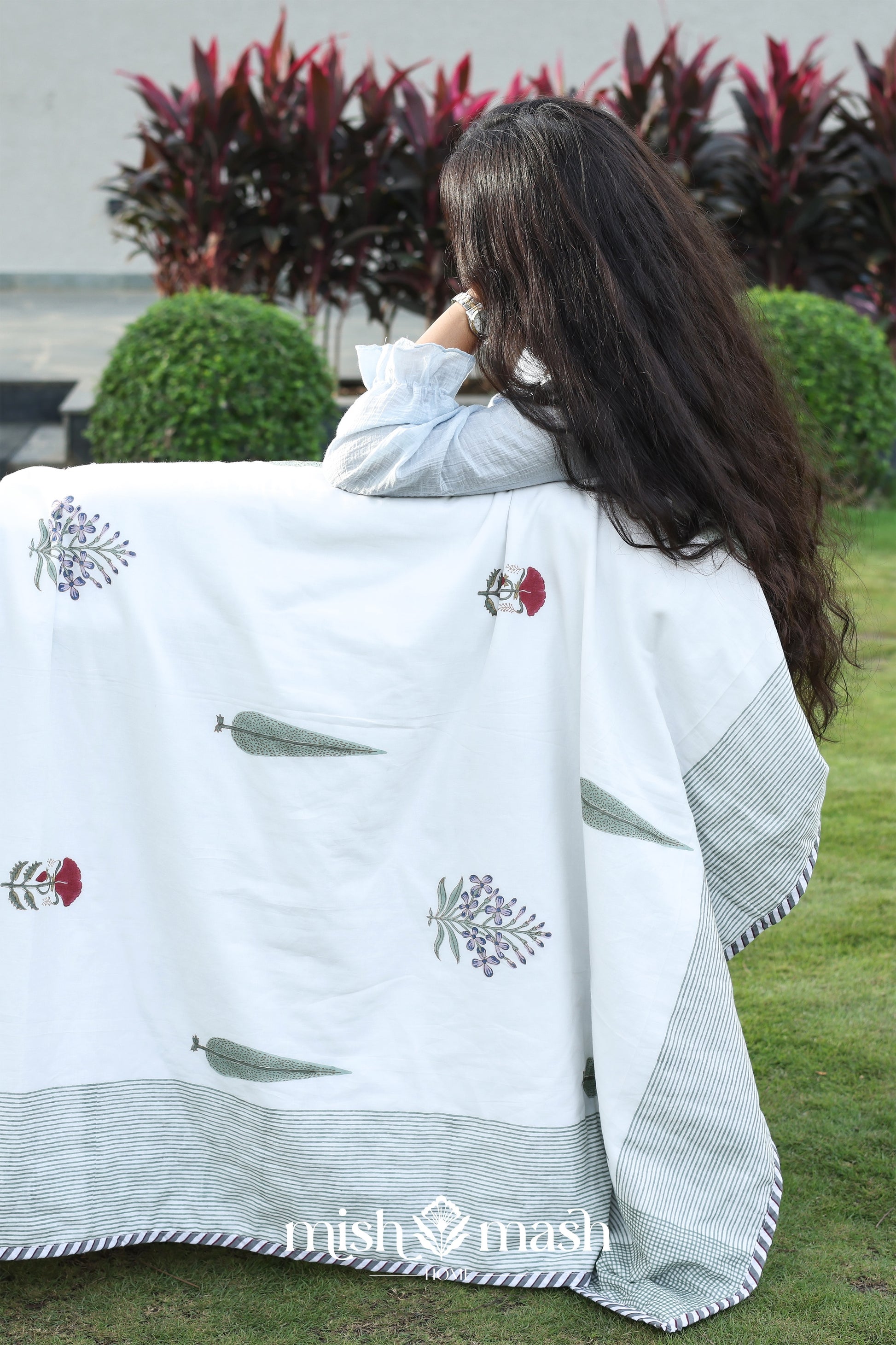 Person holding a white summer blanket with floral patterns in an outdoor setting. Buy cotton dohar blanket.