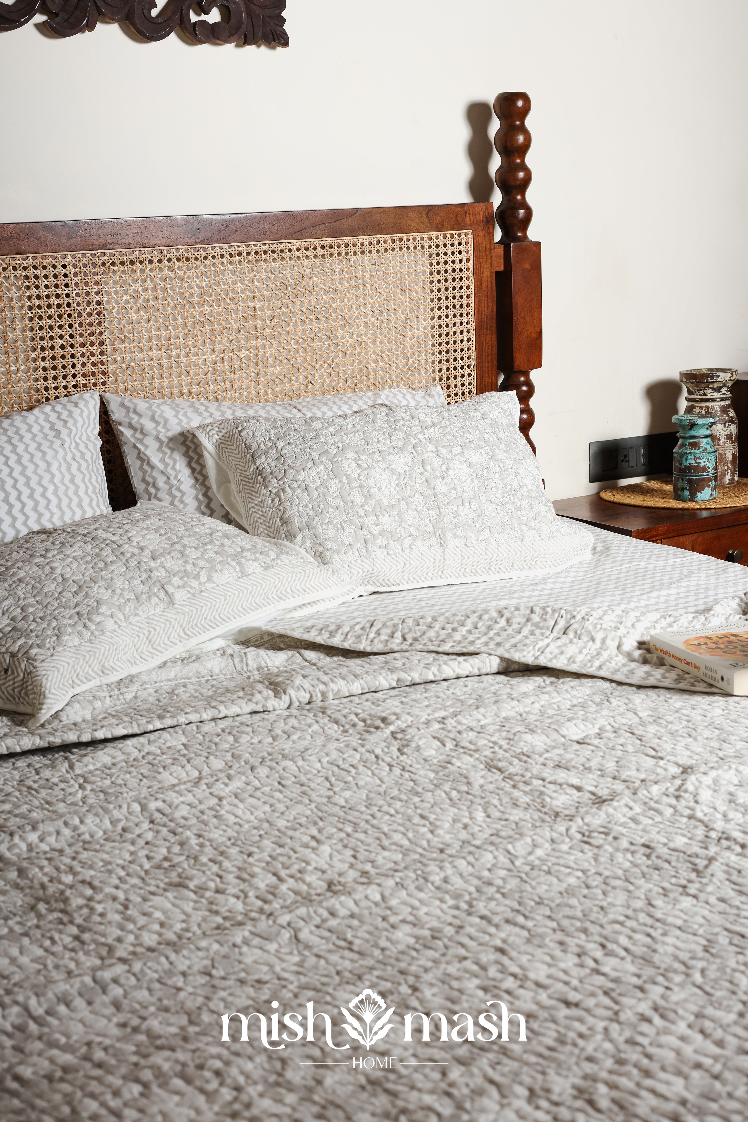 Bed with grey reversible bed spread and pillows, featuring floral design on side and chevron design on another in pure cotton