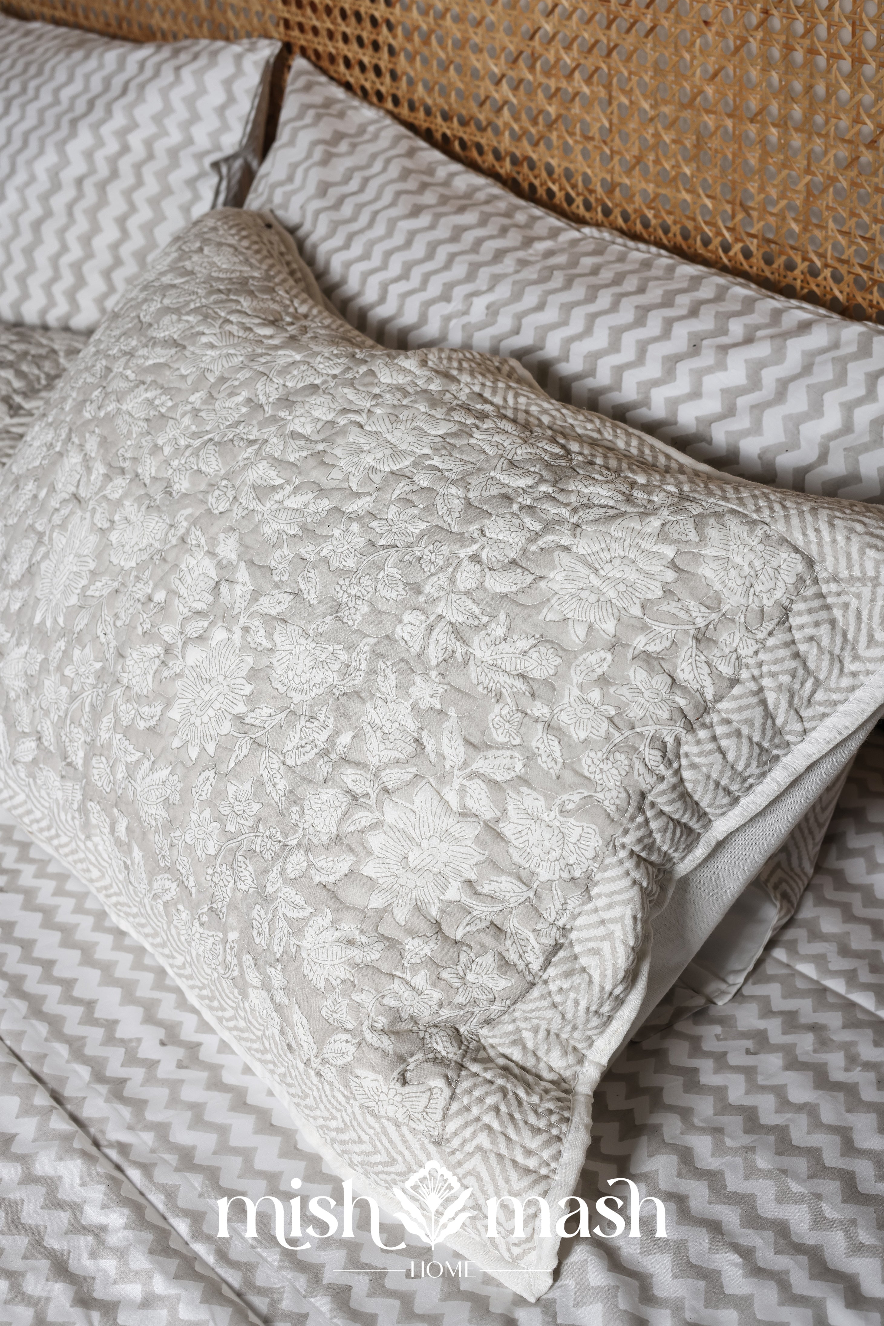 Matching cotton floral pillows on a bed with grey and white chevron print double bed sheet