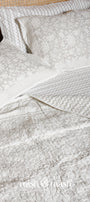 Grey reversible bed spread with chevron print on one side and floral print on another