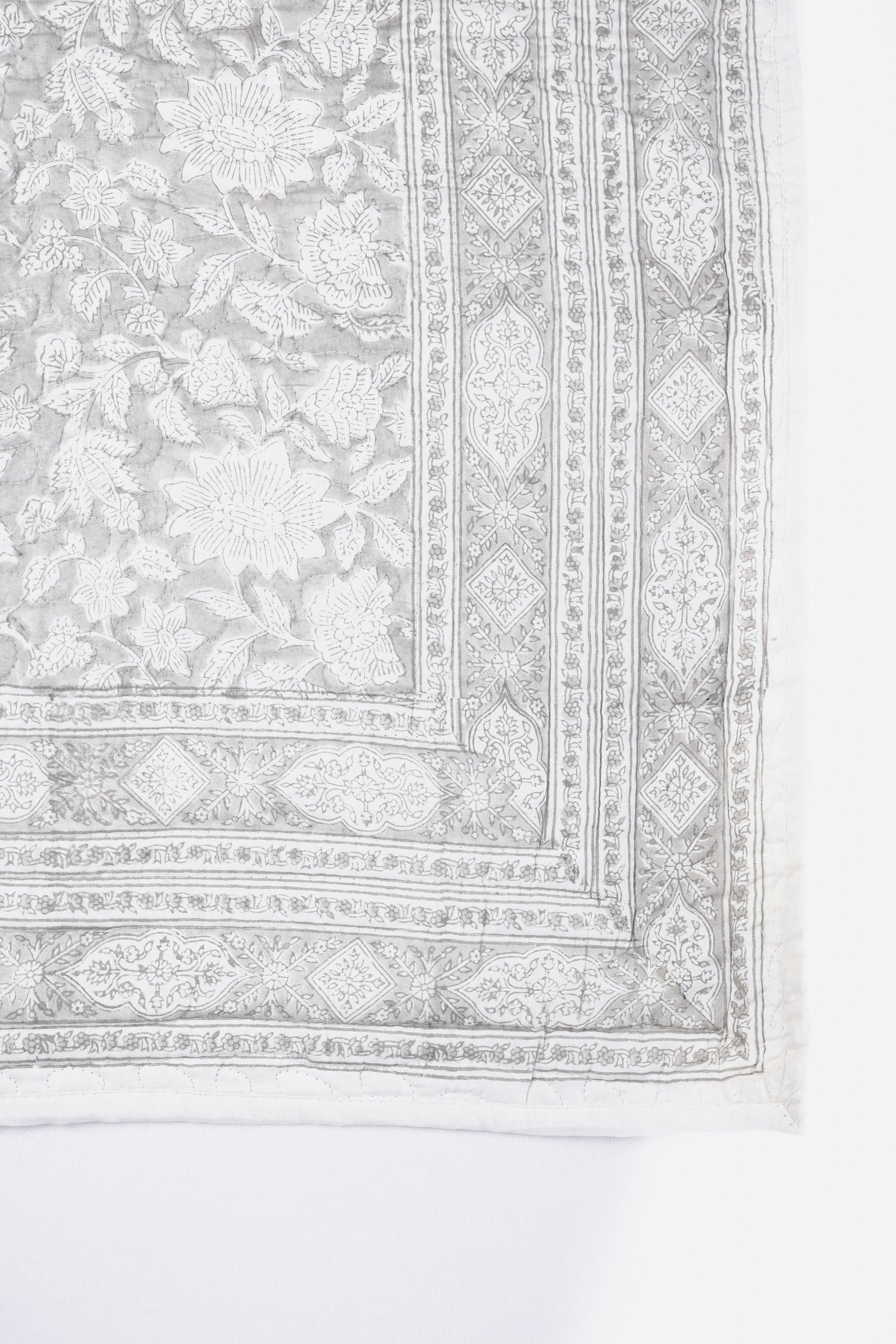 Luxury bed spread with intricate floral patterns in grey and white 