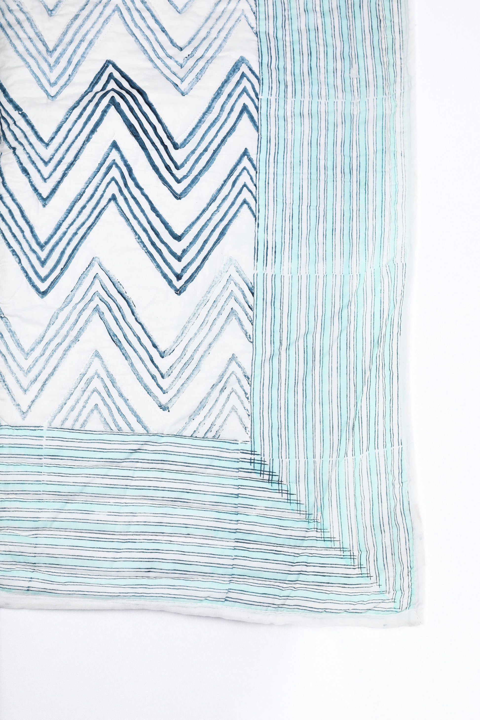 Reversible quilted cotton bed spread with blue and white zigzag pattern on a white base