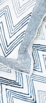 Reversible quilted bed spread with blue zigzag pattern on a white base