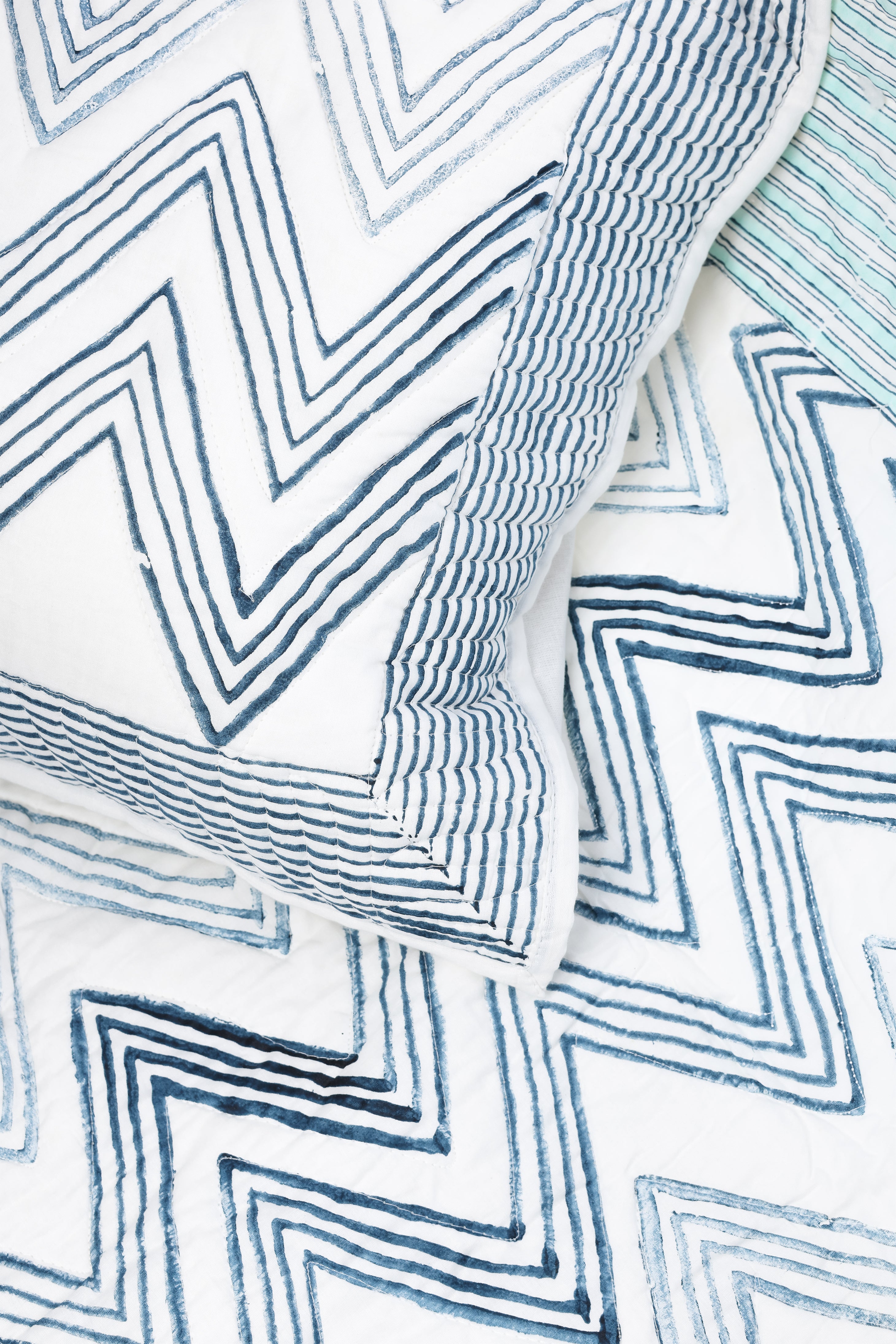 Reversible quilted bed spread with blue zigzag pattern on a white base