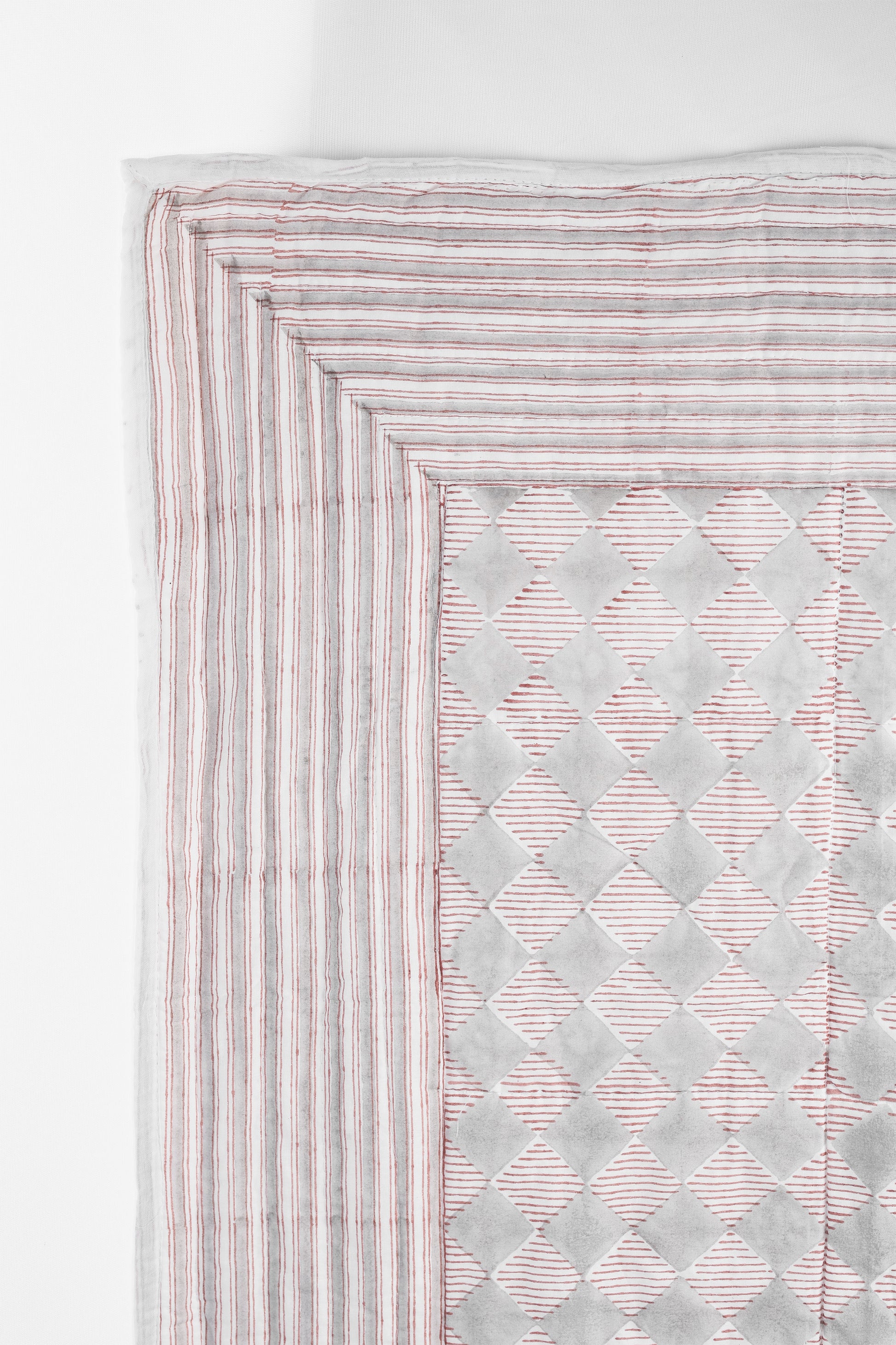 Reversible cotton bed spread with red and grey checks  on a white background on one side