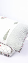 Decorative cotton pillow with floral patterns kept on a luxury cotton bedspread. 