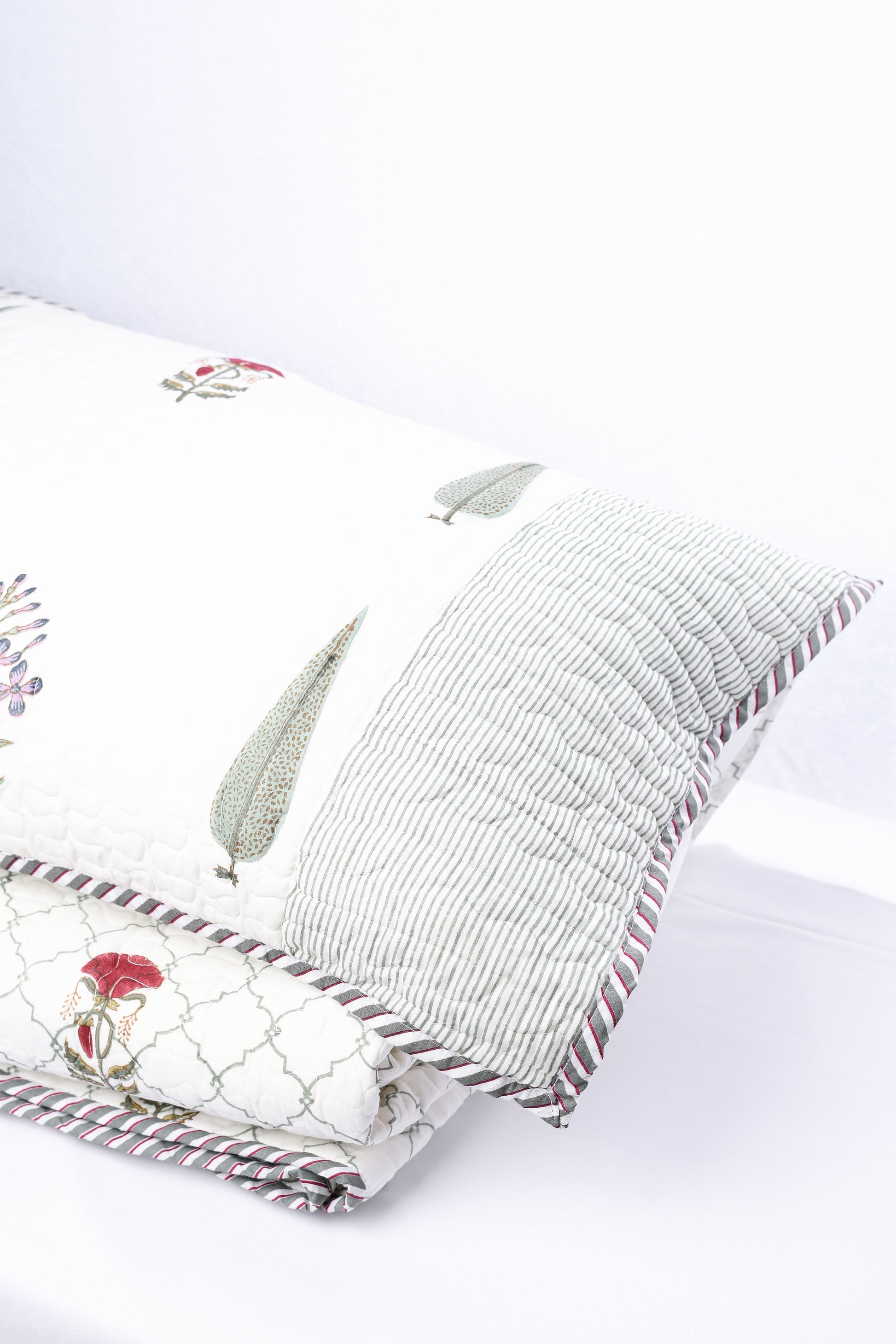 Decorative cotton pillow with floral patterns kept on a luxury cotton bedspread. 