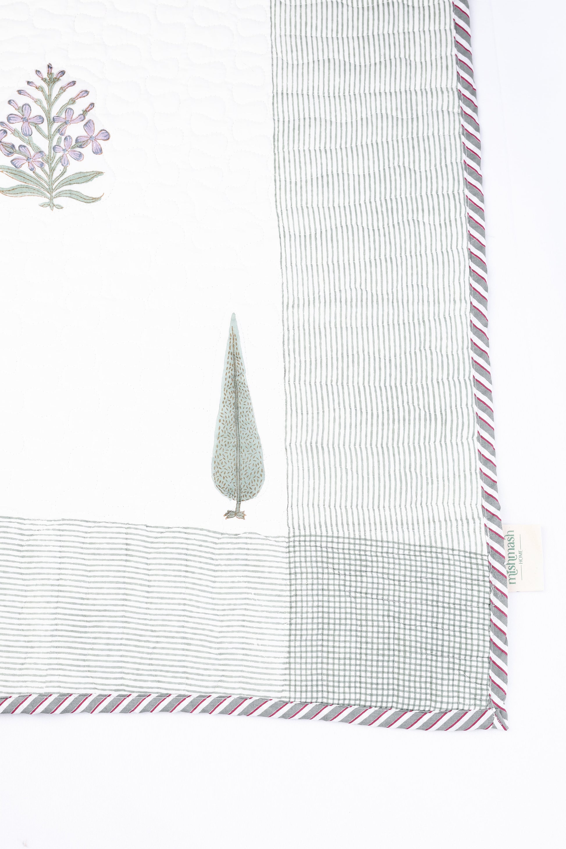 One side of a cotton bed cover with floral block print on a white background. Luxury bed spread.