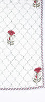 Quilted cotton bed cover with a geometric pattern and floral hand block print on a white background. Festive bedcover.