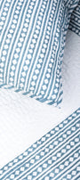 Close-up of blue and white quilted bed cover with matching cotton pillow cover. Buy luxry bedspread online.